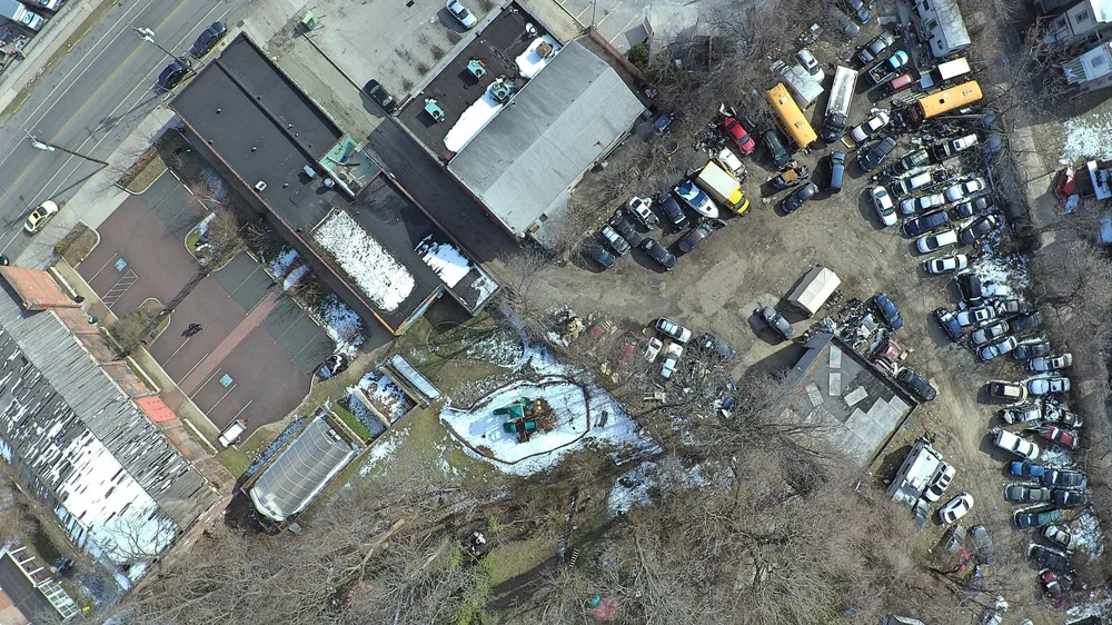Overhead view of a car lot containing several cars behind a building